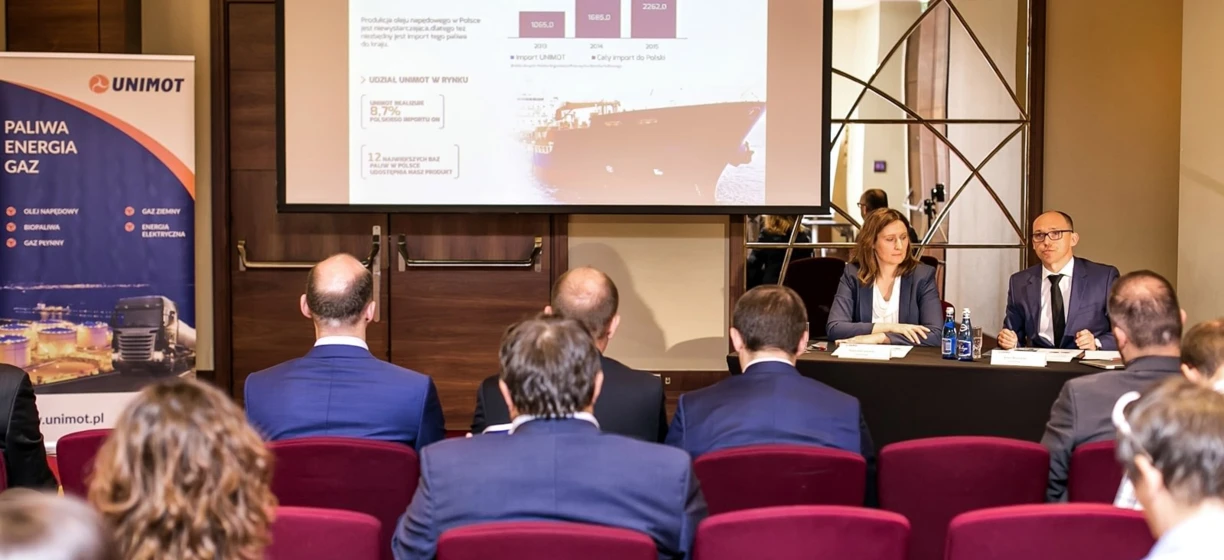 Polish Fuel and Energy Company UNIMOT showcasing their products at an event. Explore their selection of fuel, oils, and biofuels. Branding and interactive displays invite interaction with attendees.