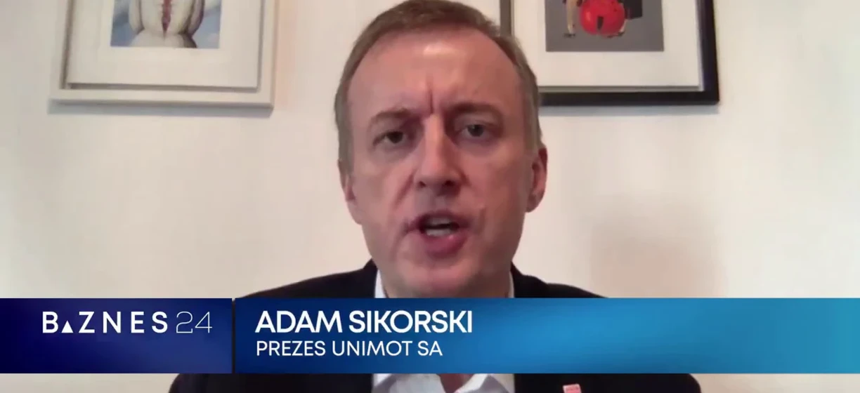 Portret Adama Sikorskiego, CEO UNIMOT SA, ubranego w elegancki garnitur z białą koszulą i krawatem. Wyrażający profesjonalizm i pewność siebie w swoim stroju.