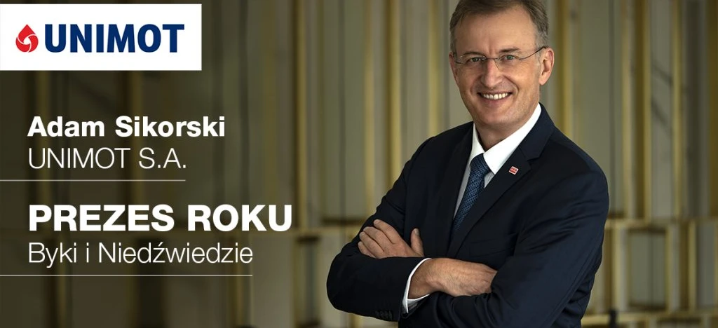 Osoba prowadząca biznes w stroju formalnym, w tym marynarce i krawacie, wręcza nagrodę dla Dyrektora Zarządzającego Roku Adamowi Sikorskiemu z UNIMOT S.A. podczas wydarzenia na Uniwersytecie Nove de Julho.