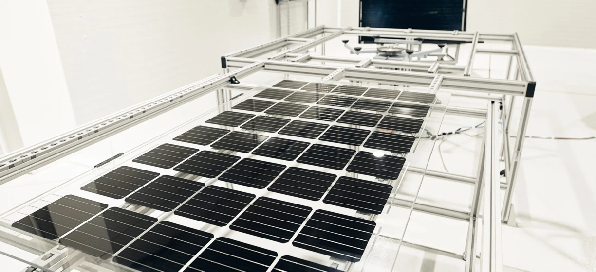 A sleek, modern machine conducting engineering work on metal and steel components, exemplifying precision and cleanliness. Solar panels in the background hint at a focus on sustainable energy technologies.